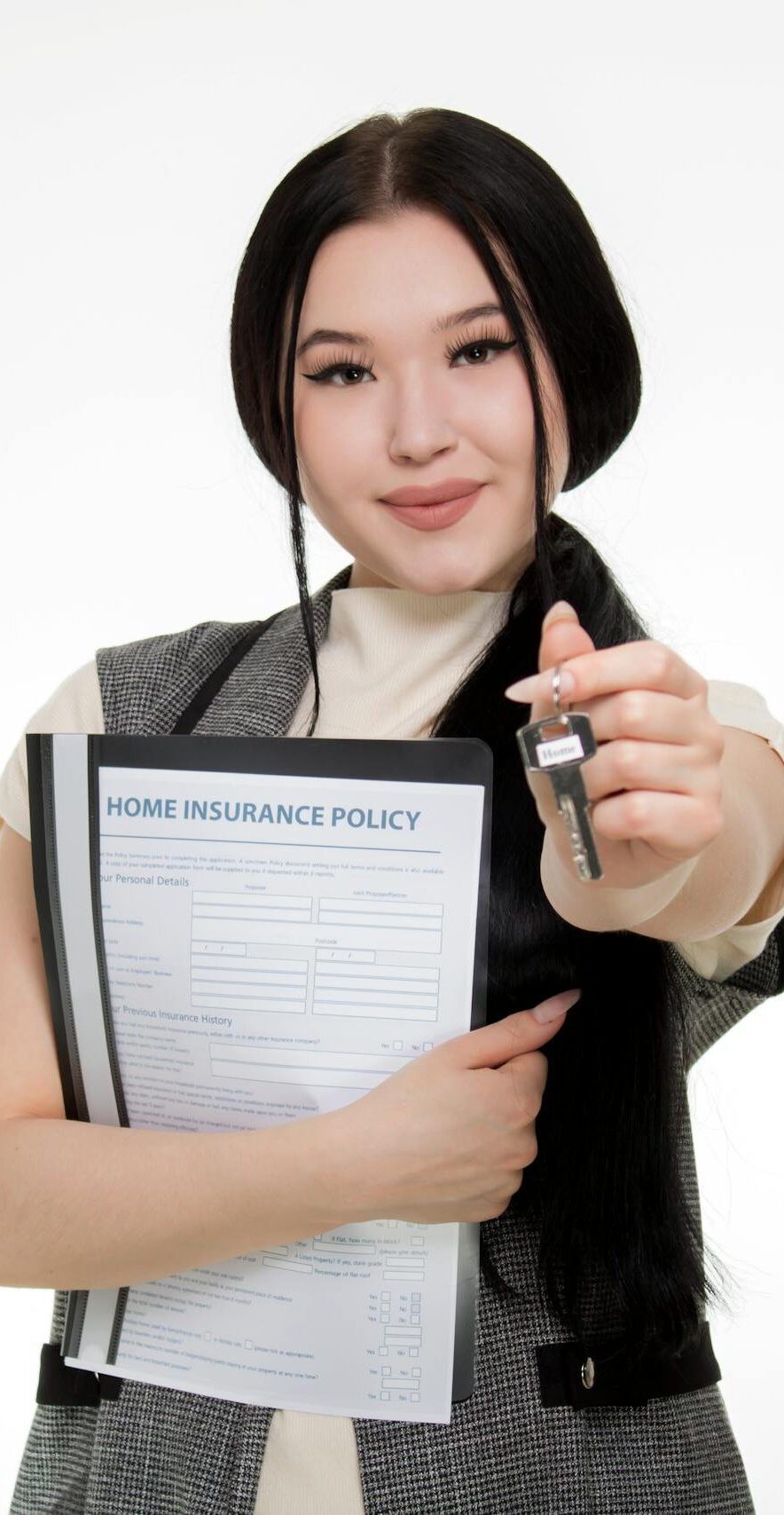 Asian woman smiling while holding a home insurance policy and a key, symbolizing new home ownership.