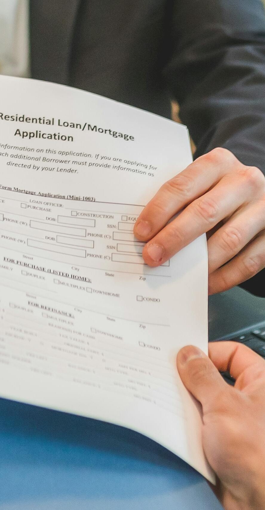 Professional setting showing hands exchanging a mortgage application document indoors.